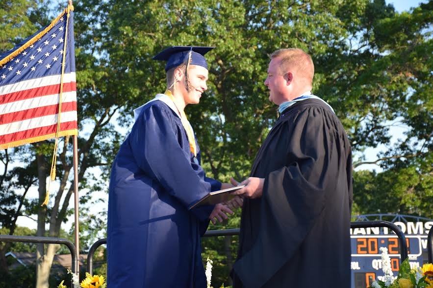 From left, Bayport-Blue Point graduate Kieran S. received his diploma from principal Robert Haas.